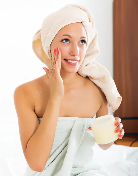 Menina aplicando creme no rosto — Fotografia de Stock