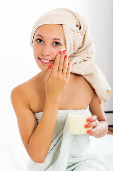 Mujer poniendo crema en la cara — Foto de Stock