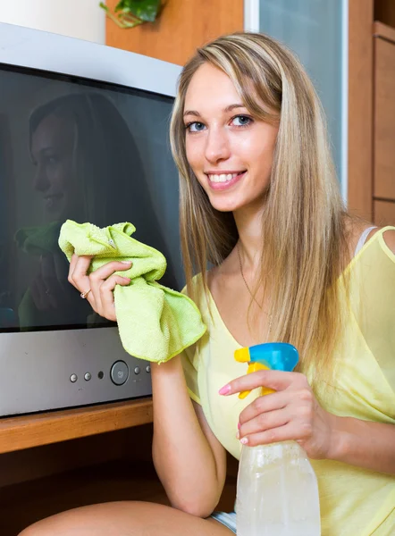 Lachende vrouw afvegen stof op Tv — Stockfoto