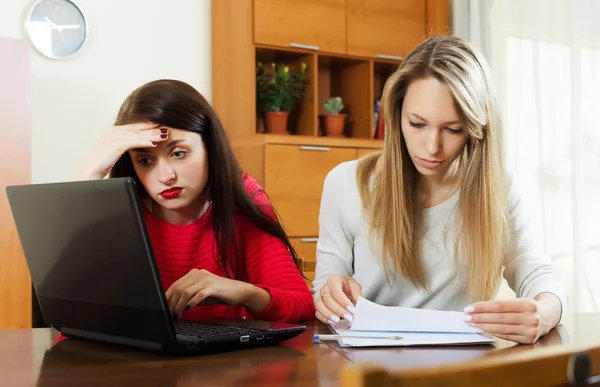 Ernstige vrouwen op zoek documenten met laptop — Stockfoto