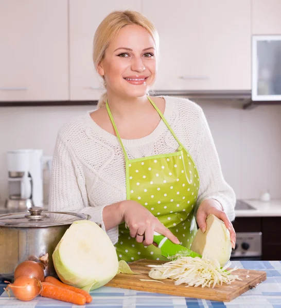 Blonde in apron chopping cabbage — Stock Photo, Image