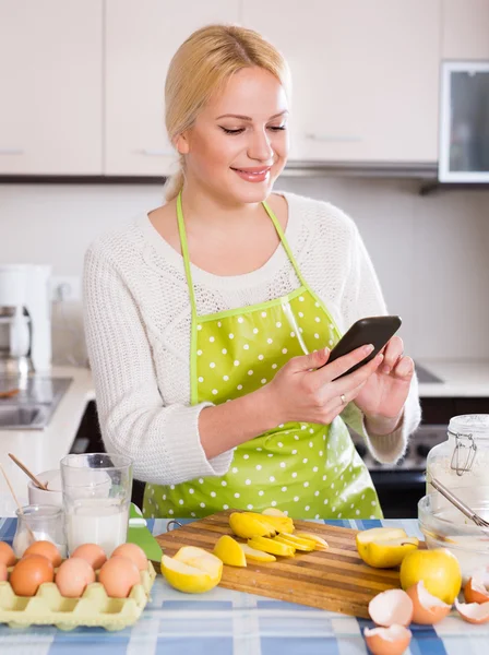 Дівчина зі смартфоном на кухні — стокове фото