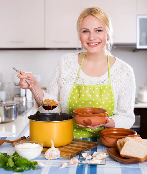 Blondin i förkläde med kött — Stockfoto