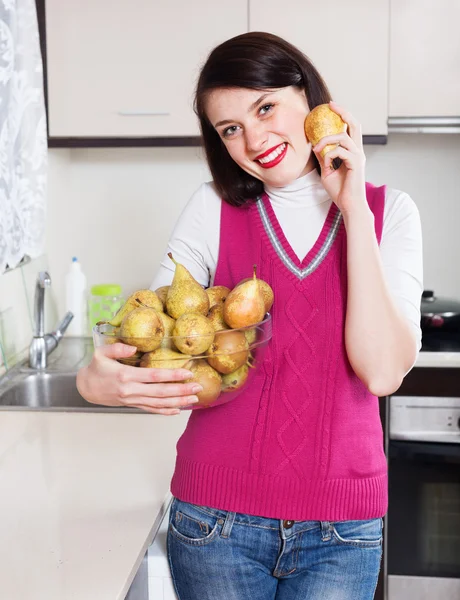 Счастливая девушка с грушами на кухне — стоковое фото