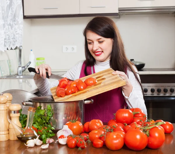 Улыбающаяся женщина готовит с помидорами — стоковое фото