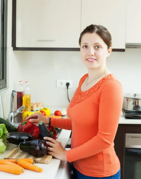 Ung hemmafru matlagning auberginer i kök — Stockfoto