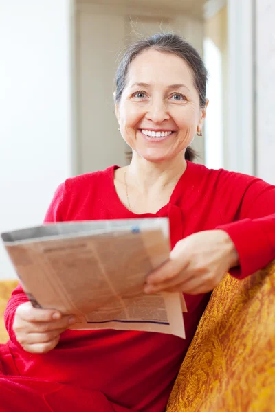 Cheerful positive mature woman reads newspaper — Stock Photo, Image