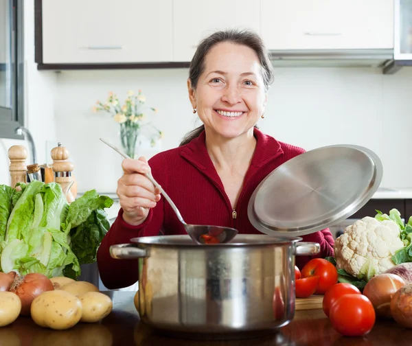 Heureuse femme mature cuisine prêté soupe diète — Photo