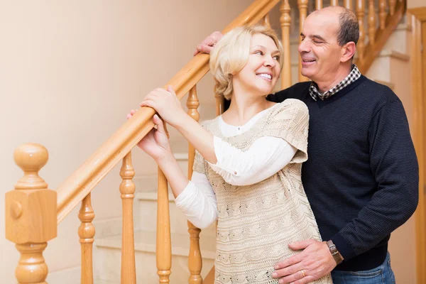 Smiling spouses leaning against stairway — Stock Photo, Image