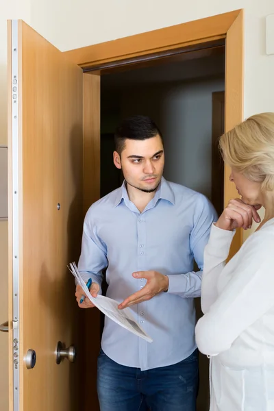 Verzamelaar en huisvrouw in de buurt van de deur — Stockfoto