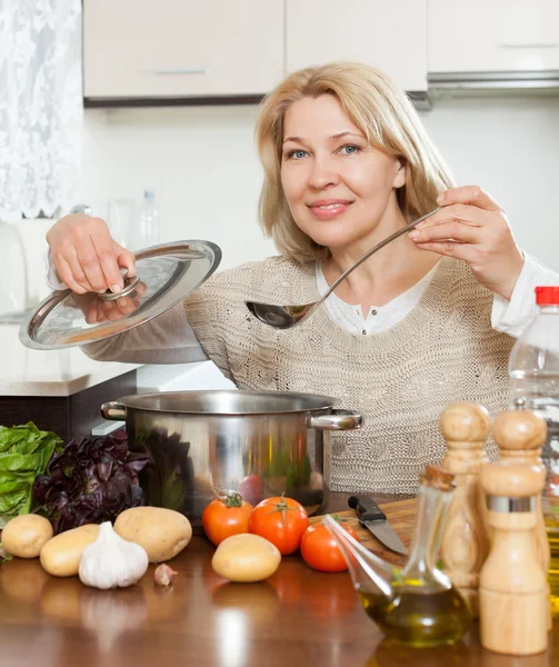 Kvinna med anteckningsboken matlagning soppa — Stockfoto