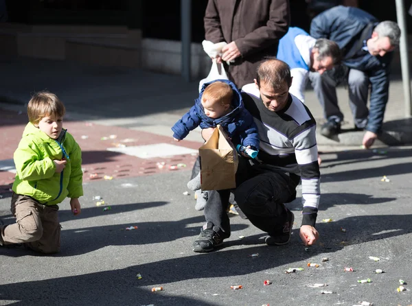 Closeup of people collecting caramels from asphalt — Stock Photo, Image