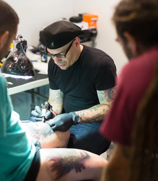 Artist doing tattoo on male client leg — Stock Photo, Image