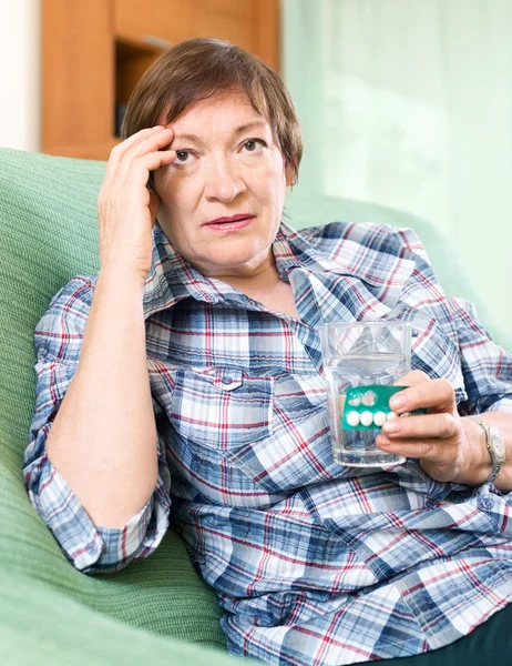 Pensionista con pastillas y vaso de agua — Foto de Stock