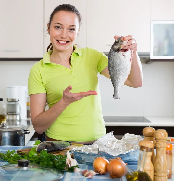 Donna che cucina pesce a casa — Foto Stock