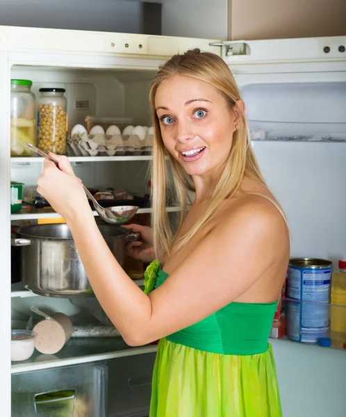 Hungrig Tjej äter soppa från pan nära kylskåp — Stockfoto