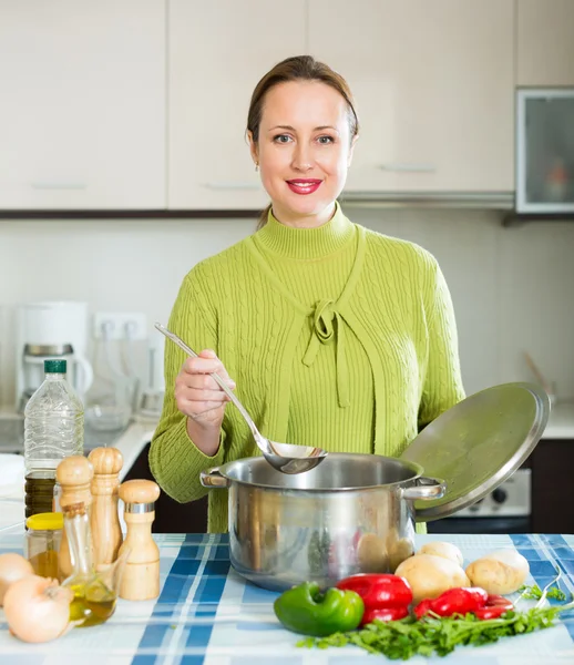 Mulher sorridente cozinhar sopa — Fotografia de Stock