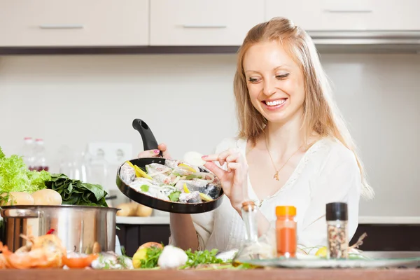 Woman putting pieces lemon to fish — Stock Photo, Image