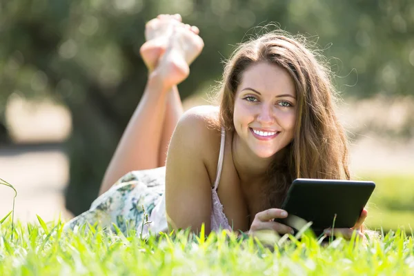 Chica acostada en la hierba con ereader —  Fotos de Stock