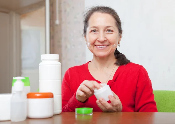 Mujer pone crema en la cara — Foto de Stock