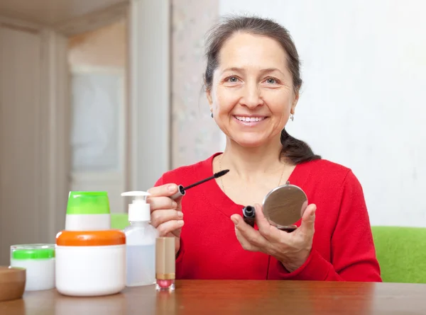 Mujer madura en rojo poniendo facepowder en su cara — Zdjęcie stockowe