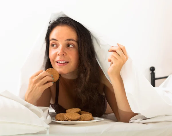 Wanita makan kue di tempat tidur — Stok Foto