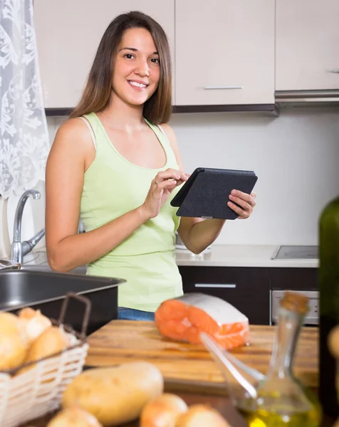 Kvinde madlavning laks med ereader - Stock-foto