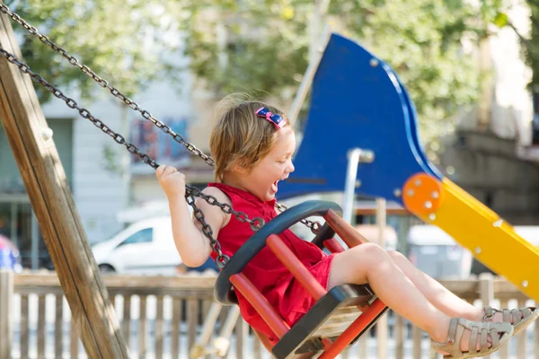 Laughing girl on chain swing — Stock Photo, Image