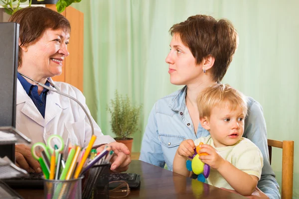 Mature  doctor talking with mother of baby — Stock Photo, Image