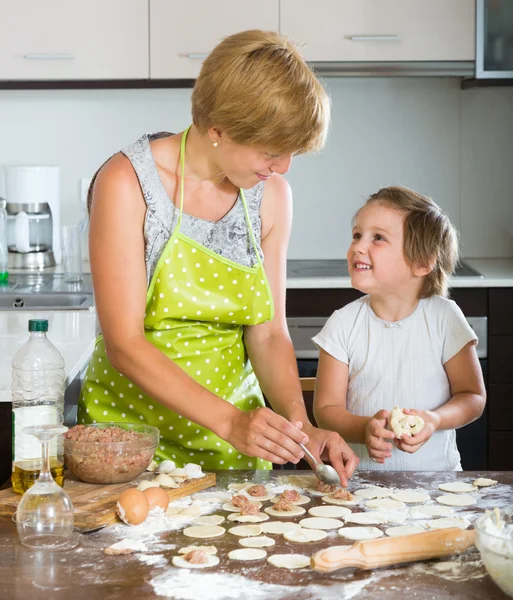 Woman with girl cooking meat dumplings — Stock Photo, Image