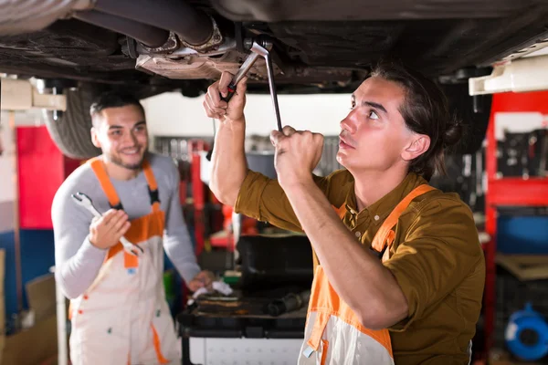 Mechanics repairing exhaust system — Stock Photo, Image