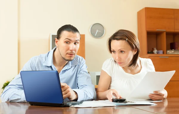 Casal procurando documentos financeiros no laptop — Fotografia de Stock