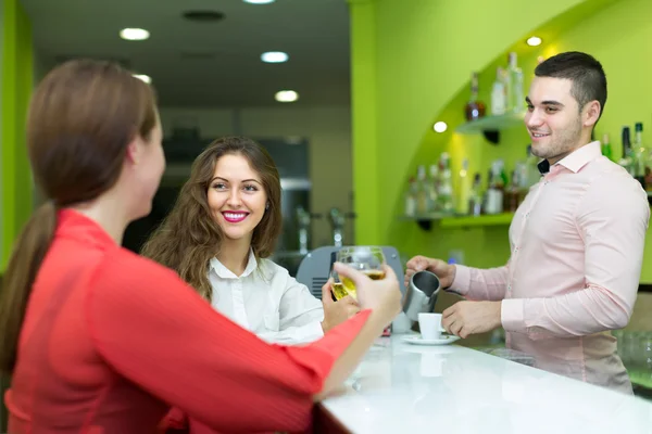 Barkeeper und lächelnde Frauen an der Bar — Stockfoto