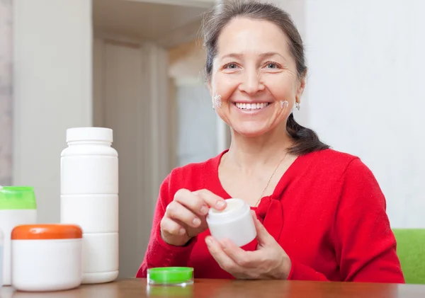 Mujer madura feliz utiliza cosmética — Foto de Stock