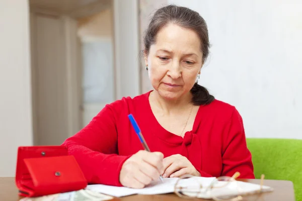 Mujer madura llena facturas de servicios públicos — Foto de Stock