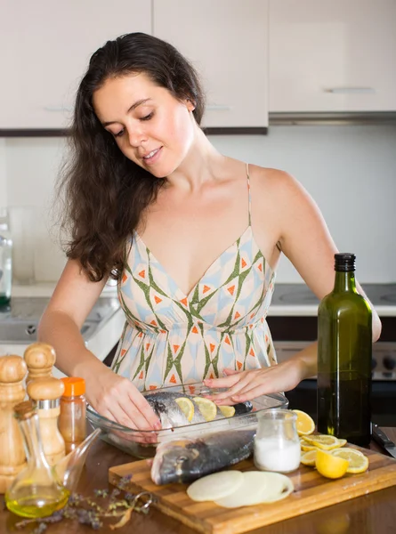 Mulher cozinhar peixes na cozinha — Fotografia de Stock