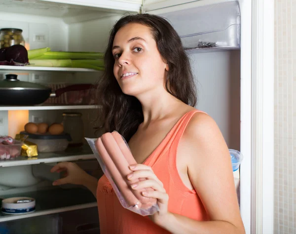 Woman taking sausages from refrigerator — Stock Photo, Image