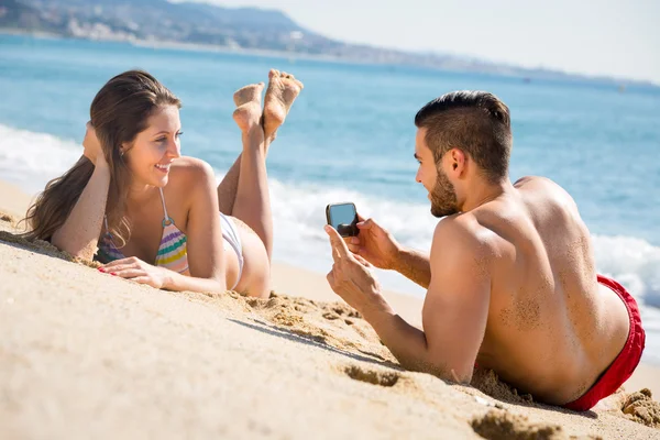 Homem tirando foto de mulher na praia — Fotografia de Stock