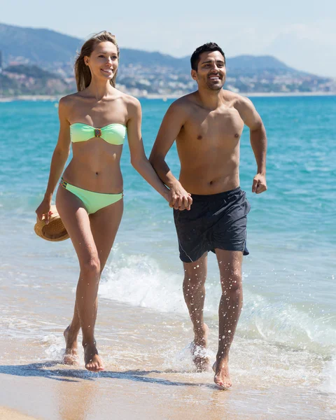 若いカップルがビーチで実行しています。 — ストック写真