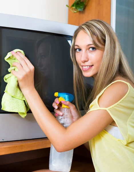 Lächelnde Frau wischt im Fernsehen den Staub ab — Stockfoto