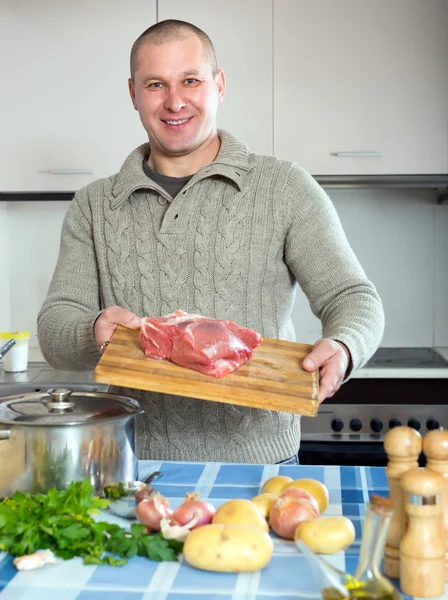 Homem com carne e legumes na cozinha — Fotografia de Stock