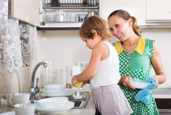 Menina ajudando a mãe lavar pratos — Fotografia de Stock