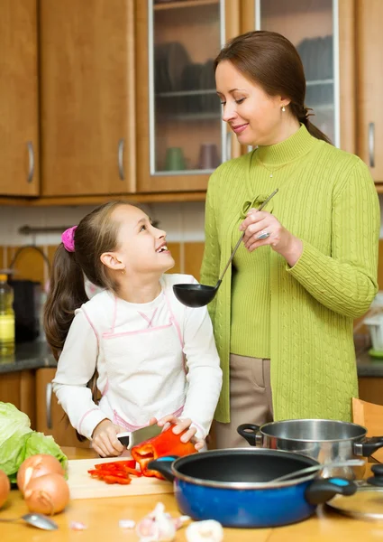 Girl and mother making soup Royalty Free Stock Photos