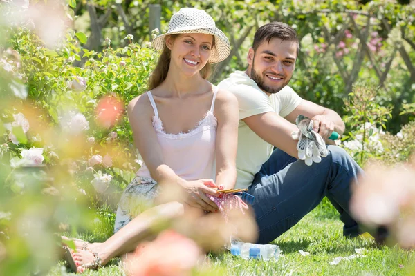 Pár odpočívá na trávě po gardenin — Stock fotografie