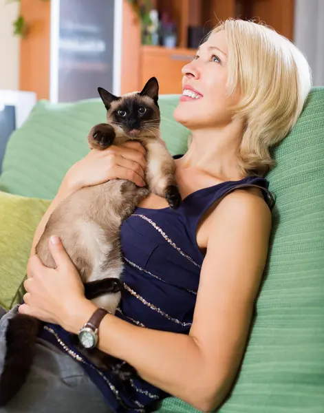 Mujer sentada en un sofá con su gato — Foto de Stock