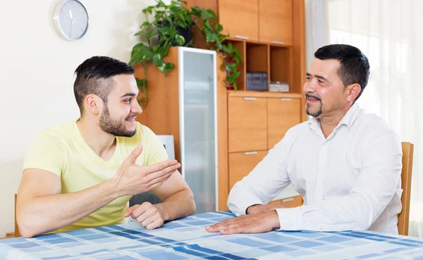 Dois parentes do sexo masculino conversando dentro de casa — Fotografia de Stock