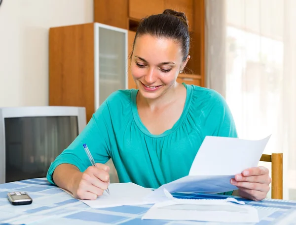 Girl with papers at the table at home — Stock Photo, Image