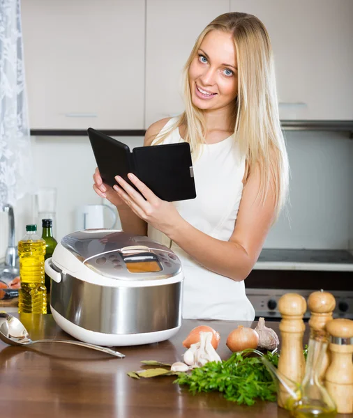 Žena čtení ereader poblíž multicooker — Stock fotografie