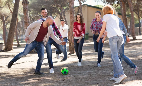 Positive adults chasing ball outdoors — Stock Photo, Image