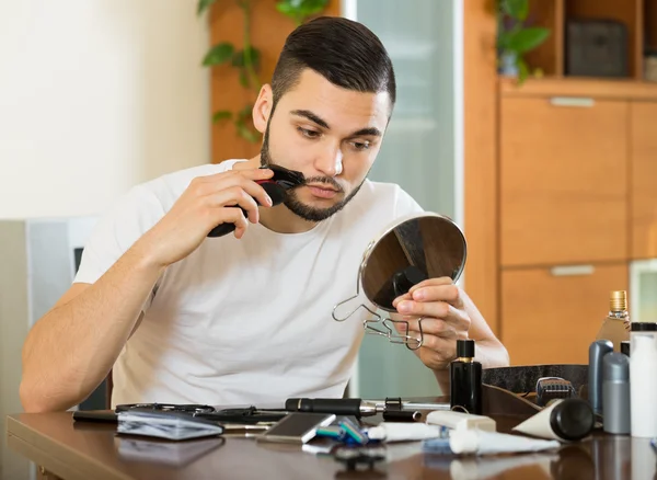 Killen tittar på spegeln och rakning skägget med trimmern — Stockfoto